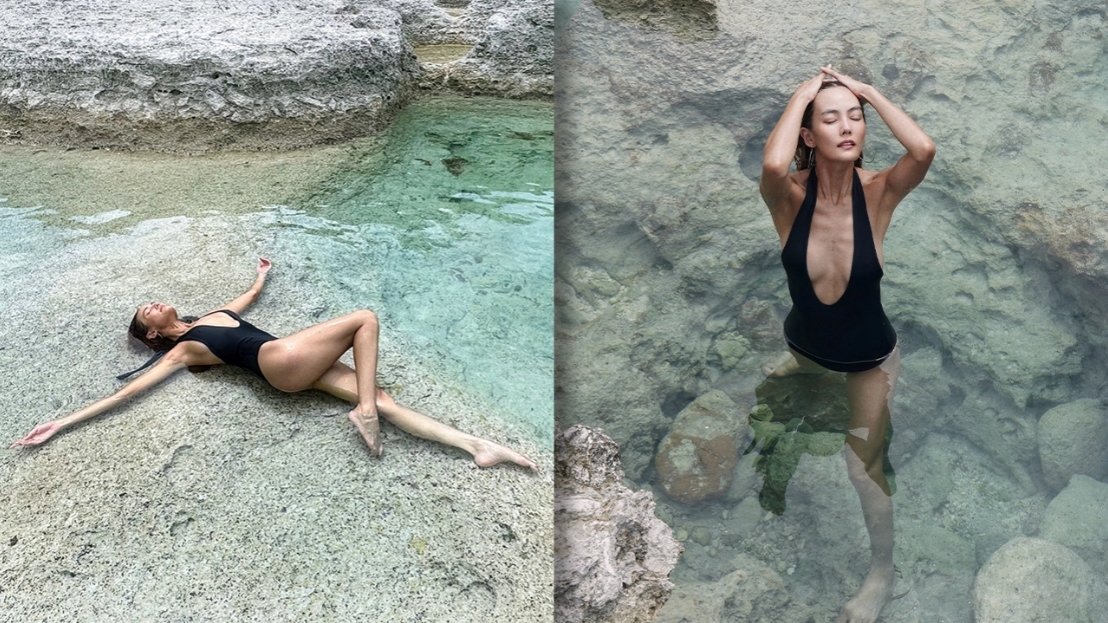 Jenny Tianphothisawan poses by the sea in a black one-piece swimsuit with a plunging neckline, showing off her slim, slender figure.